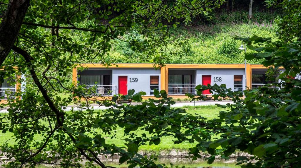 a house with red doors in a yard with trees at Cocoon Hotel Belair in Bourscheid