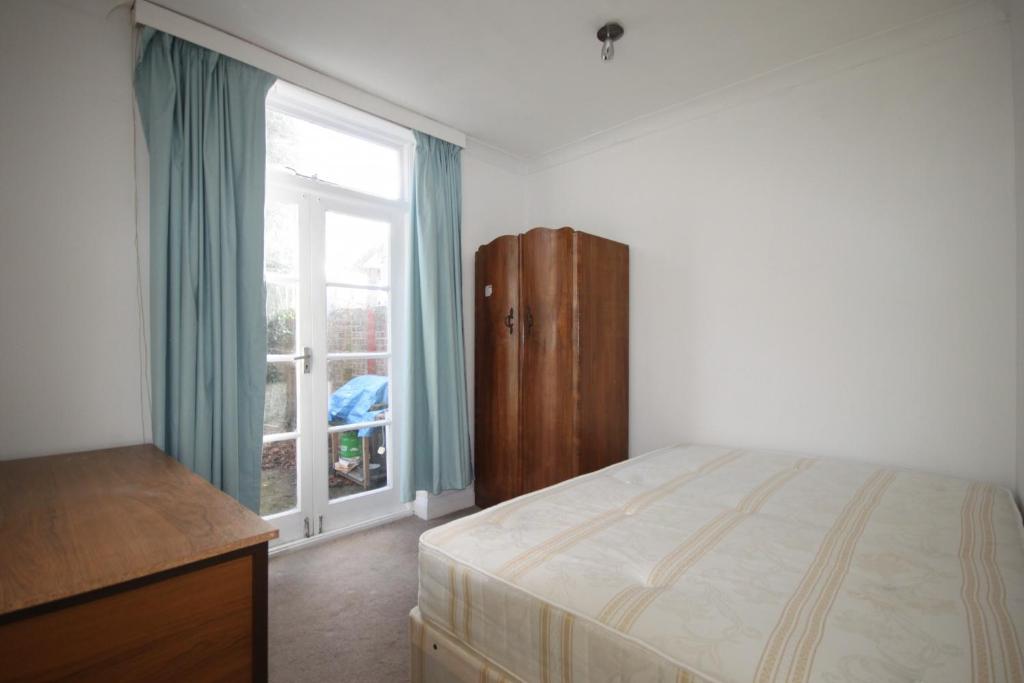 a bedroom with a bed and a large window at Hill Crescent in London