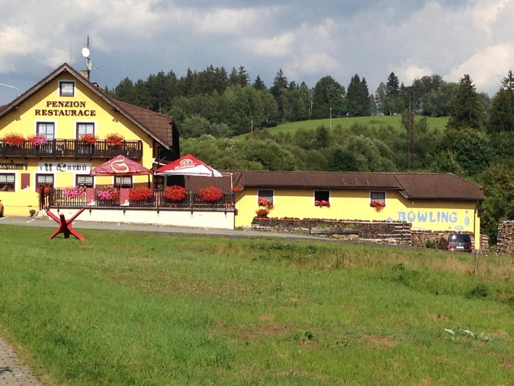 a yellow building with a red star in a field at Penzion U Larvů in Železná Ruda