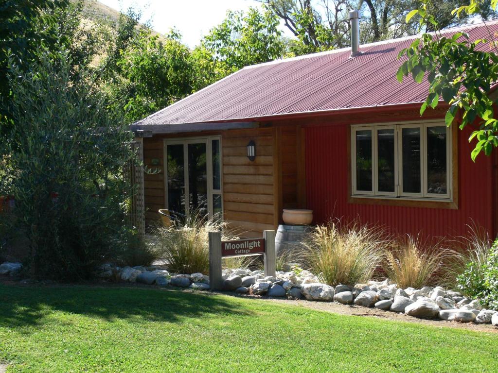 Burn Cottage Retreat في كرومويل: منزل احمر وامامه لافته