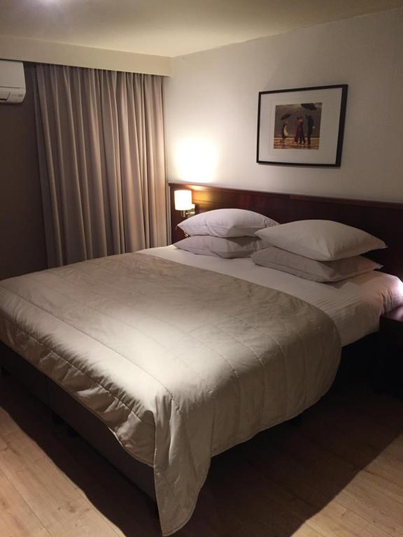 een slaapkamer met een groot bed met witte lakens en kussens bij Hotel Prélude in Aalter