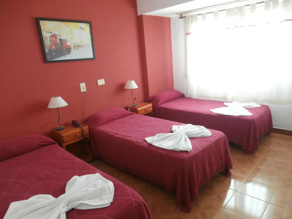 two beds in a room with red walls at Hotel El Circulo in Mar del Plata