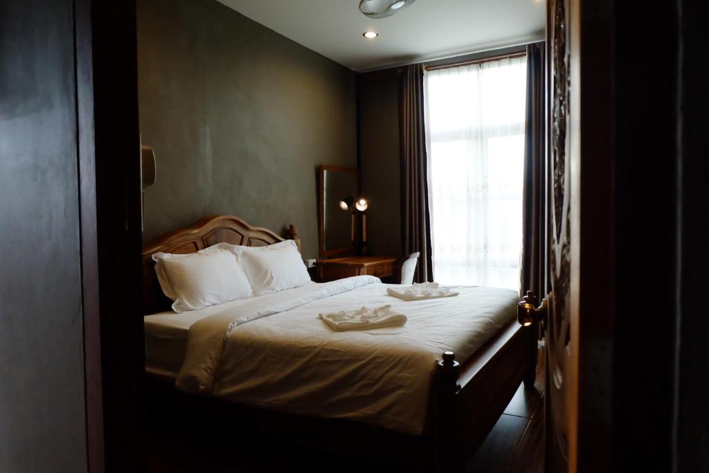 a bedroom with a large bed with a window at Bloom Cafe & Hostel in Ko Lipe