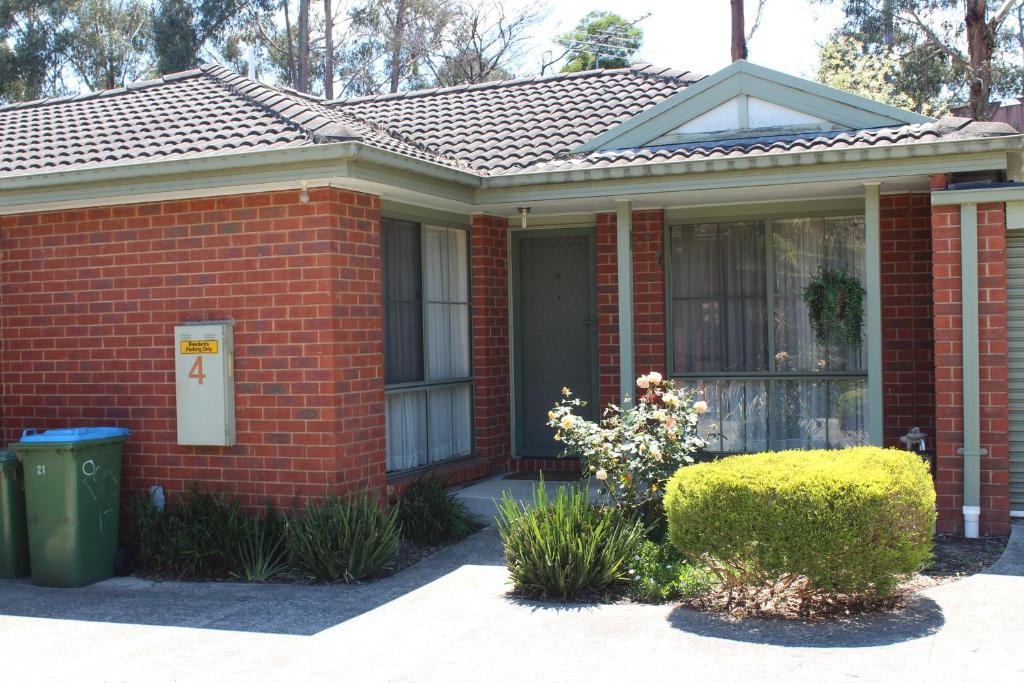 a red brick house with a green trash can in front of it at Australian Home Away Ringwood Bardia in Ringwood