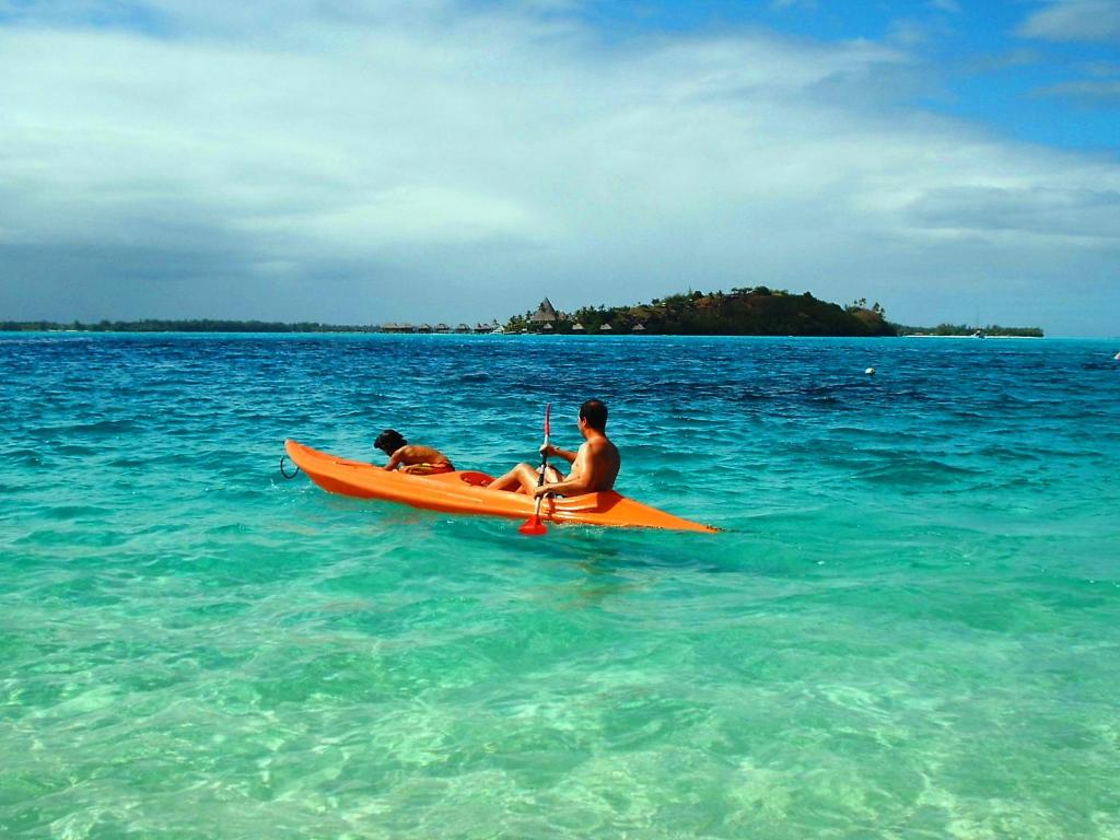 two people on an orange kayak in the ocean at Village Temanuata in Bora Bora