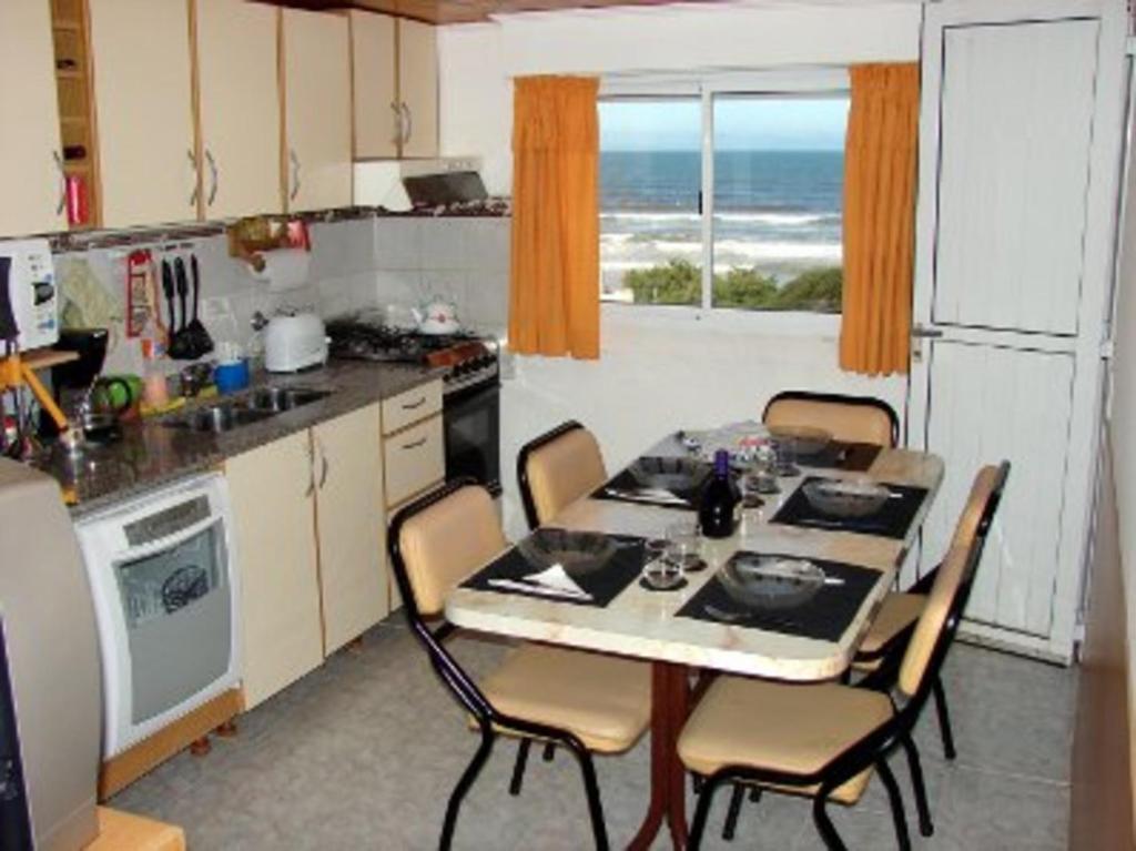 una cocina con mesa y sillas y una cocina con el océano en MarWal Departamentos en Santa Teresita