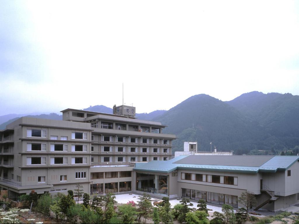 a large building with a mountain in the background at Hotel Kameya in Osaki