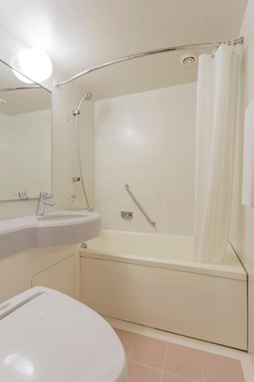 a bathroom with a toilet and a tub and a sink at Mitsui Garden Hotel Kumamoto in Kumamoto