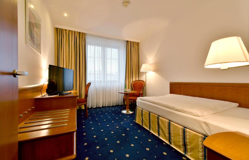 une chambre d'hôtel avec un lit et une télévision dans l'établissement Hotel Coronet, à Prague