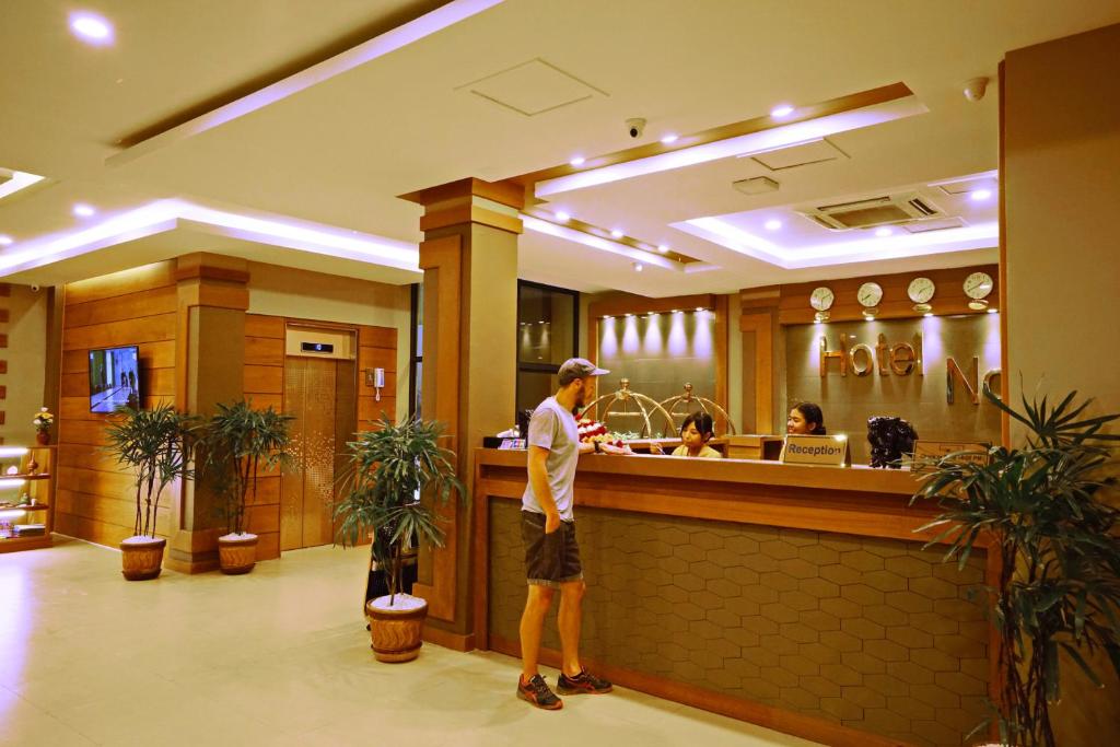 ein Mann, der an einer Bar in einem Restaurant steht in der Unterkunft The Hotel Nova in Mandalay