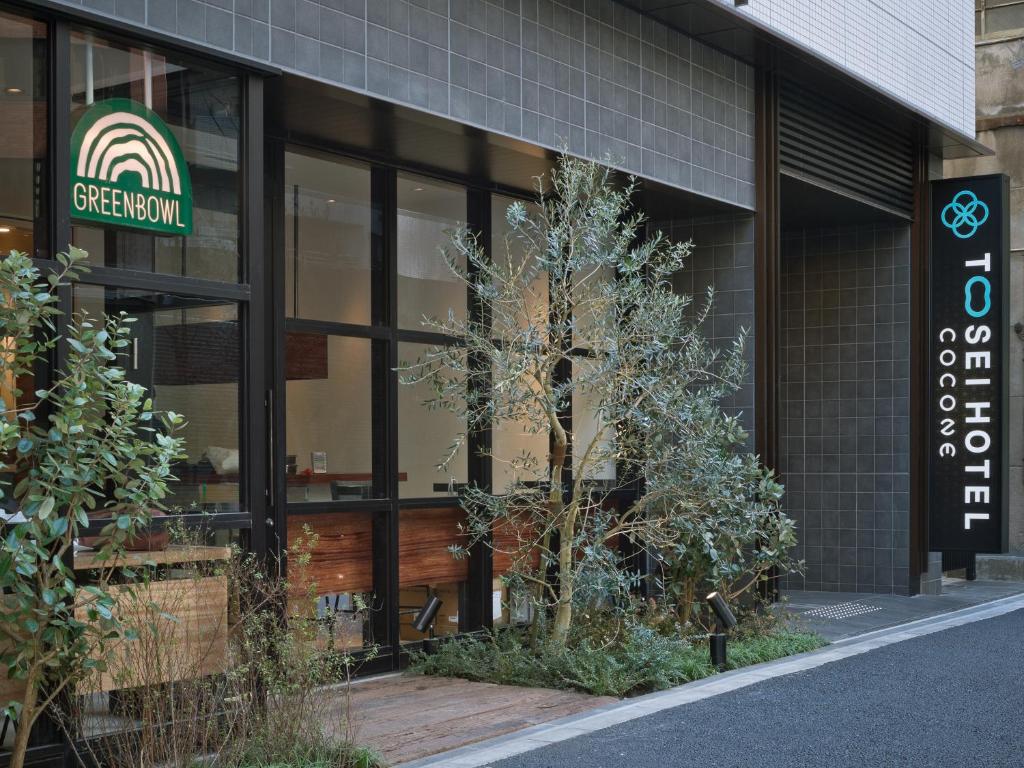 a building with a tree in the front of it at Tosei Hotel Cocone Kanda in Tokyo