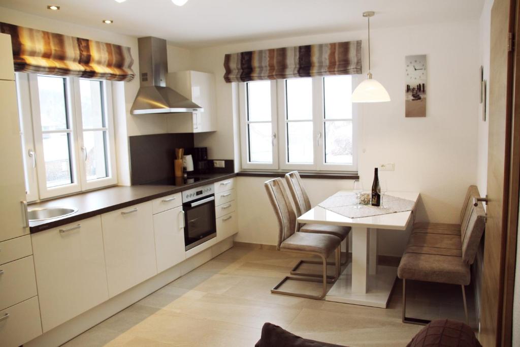 uma cozinha com mesa, cadeiras e janelas em Apartments Fuchs em Grundlsee