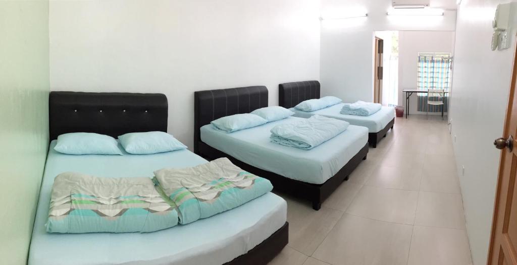 Habitación con 3 camas y almohadas azules. en Ipoh TZY's Homestay en Ipoh