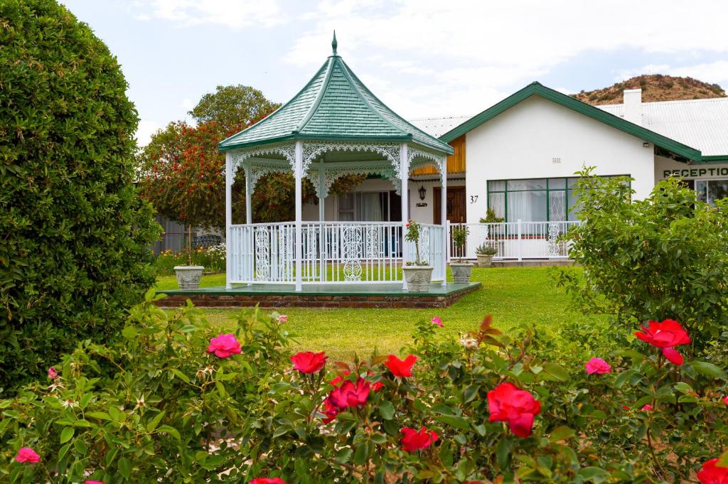 Casa blanca con cenador y rosas rojas en Colesview Guest House, en Colesberg