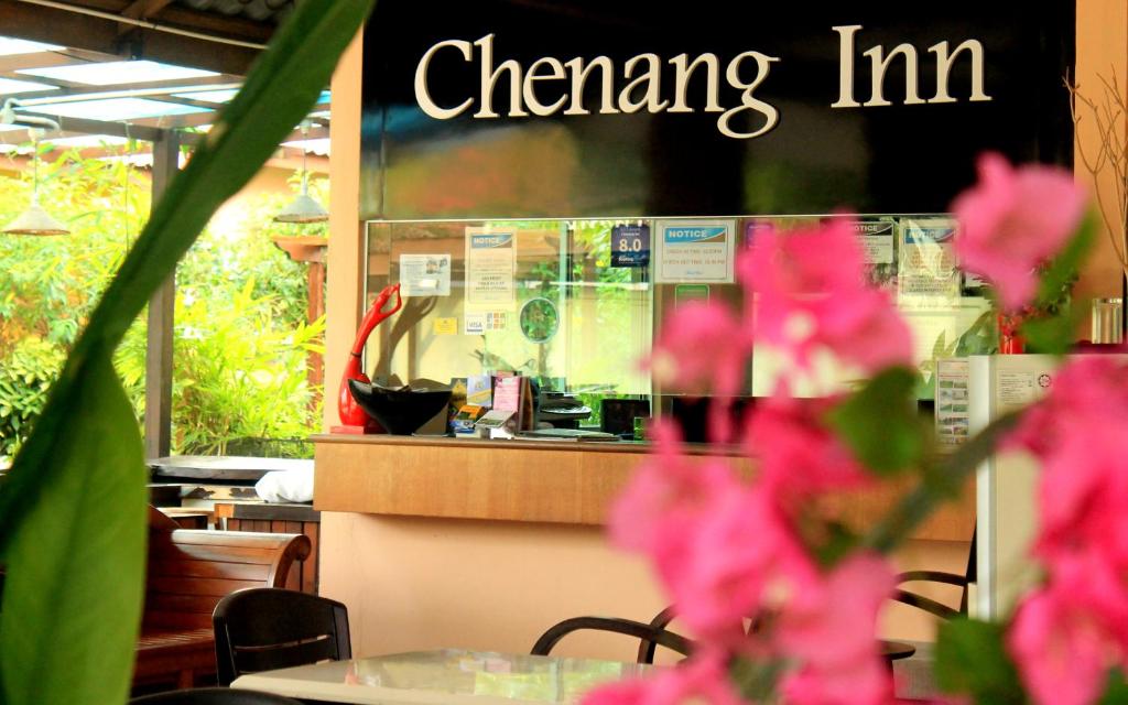 a restaurant with pink flowers in front of a counter at Chenang Inn in Pantai Cenang