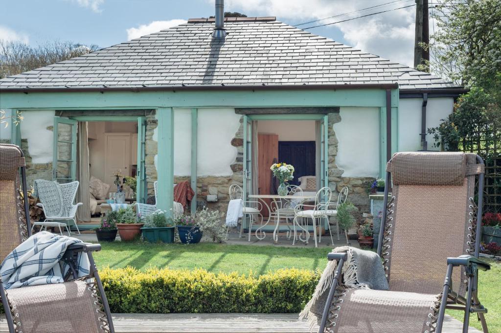 a cottage with a table and chairs in a yard at The Potting Shed in Newquay