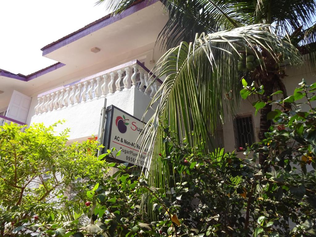 a sign on the side of a building with trees at Sugar Plum Macedo Palms in Baga