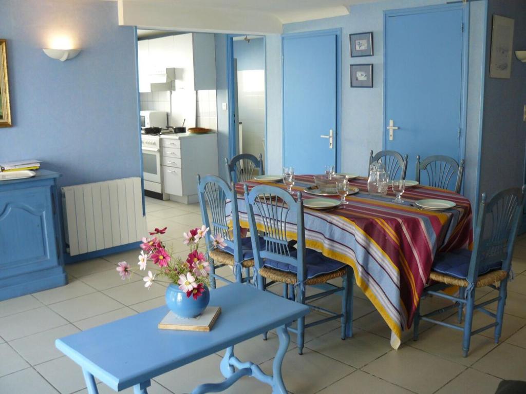 a dining room with a table and chairs and a kitchen at En Dro, Rez-de-jardin à Carnac in Carnac