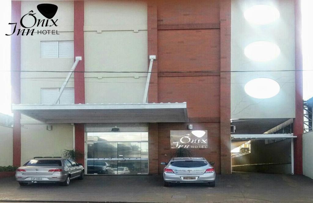 Teodoro SampaioOnix Inn Hotel的两辆汽车停在一栋建筑物前