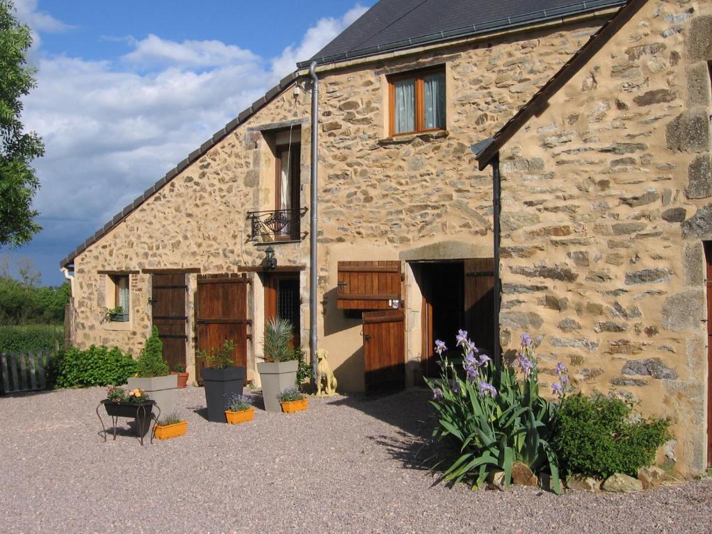 une ancienne maison en pierre avec des fleurs devant elle dans l'établissement Domaine du Breuil, à Chassignolles