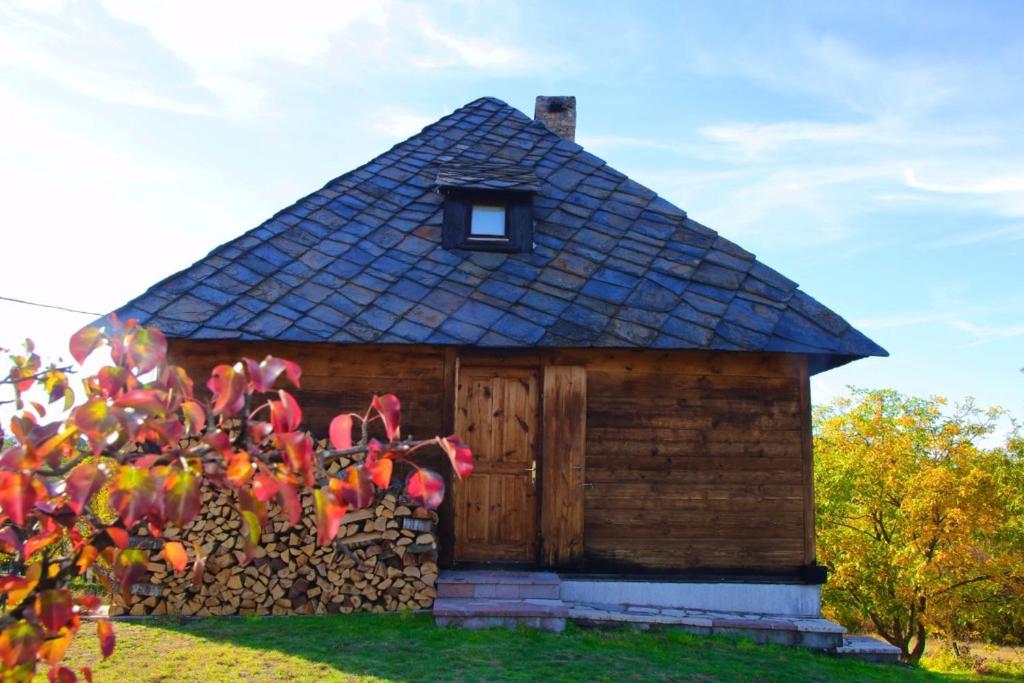 a small house with a roof and a stone wall at Cabin Menka in Sirogojno