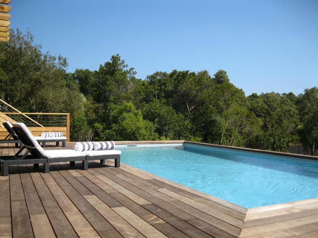 a swimming pool with two lounge chairs on a wooden deck at Maison d' Hôtes L'Aria Mezzana in Sainte-Lucie de Porto-Vecchio