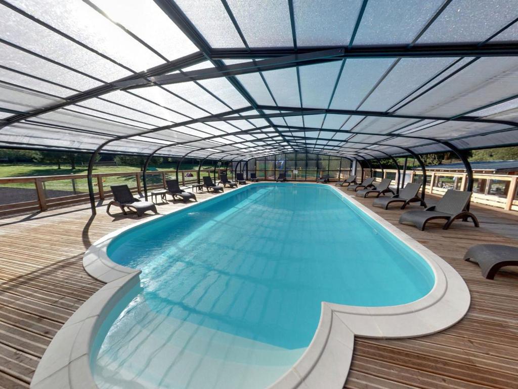 uma grande piscina com cadeiras e um telhado em Camping Les Vernieres La Bourboule Sancy em La Bourboule