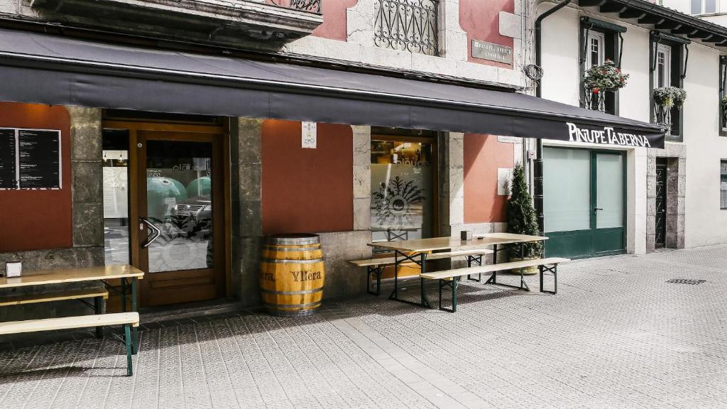 un restaurante con bancos frente a un edificio en Hotel Piñupe en Lekeitio