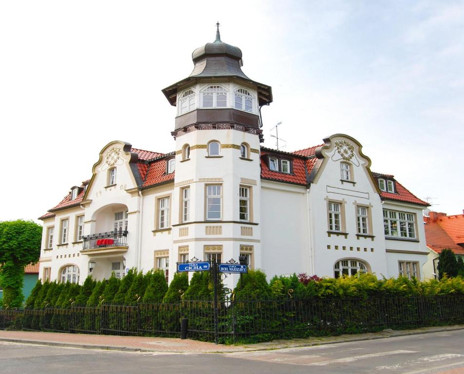 Un bâtiment blanc avec une tour en haut dans l'établissement Villa Richter, à Międzyzdroje