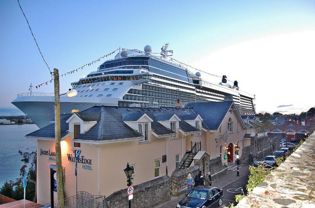 ein Kreuzfahrtschiff liegt neben einem Gebäude vor Anker in der Unterkunft WatersEdge Hotel in Cobh