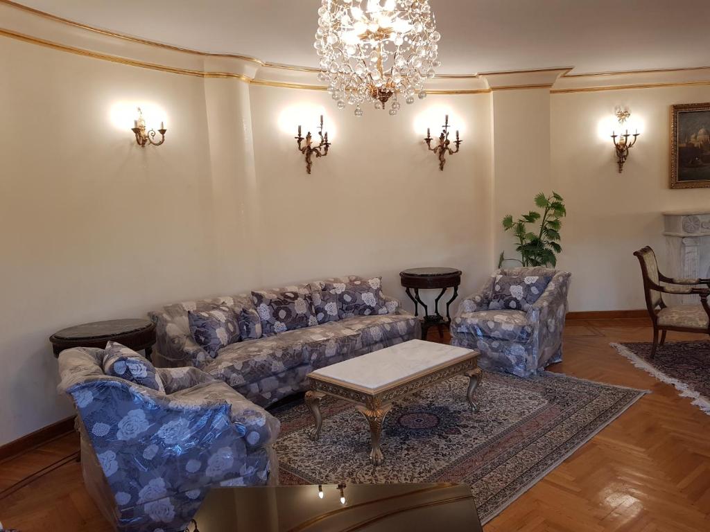 uma sala de estar com sofás e um lustre em Choueifat Residence Families Only no Cairo