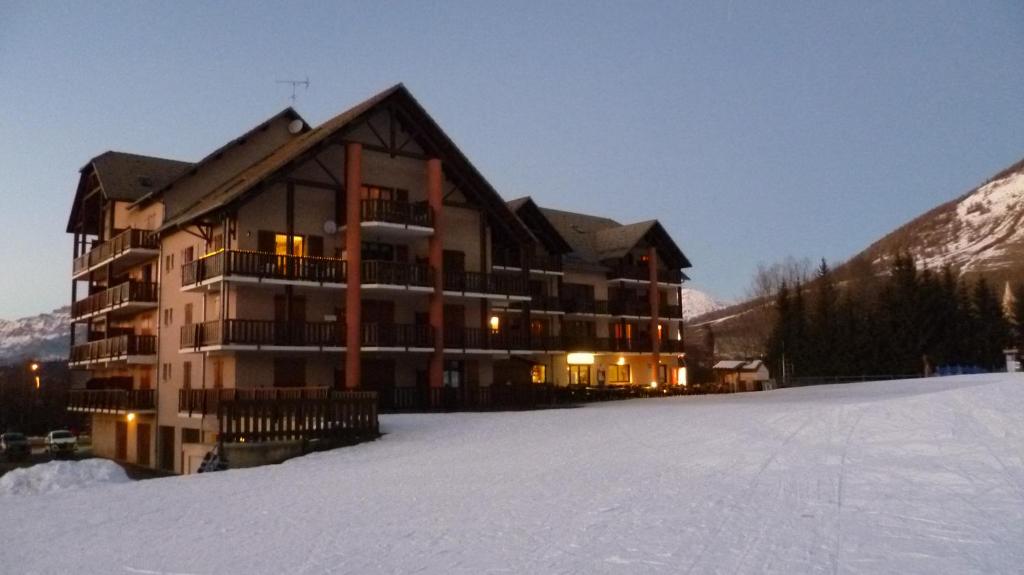 un grand bâtiment dans la neige devant dans l'établissement Résidence Les Ecrins, à Ancelle