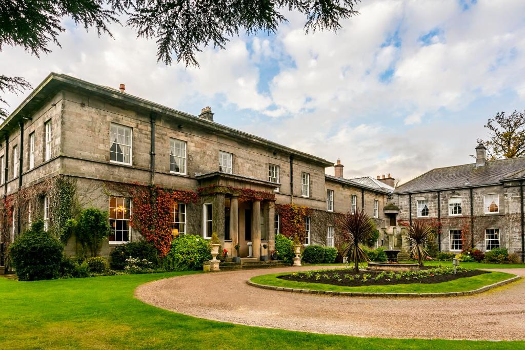 an exterior view of a large stone building with a circular driveway at Doxford Hall Hotel And Spa in Alnwick