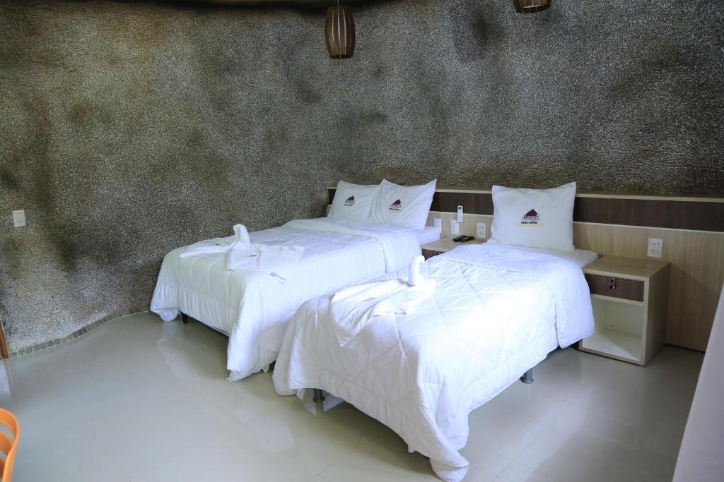 two beds in a hotel room with white sheets at Pousada Pedra Grande in Morros