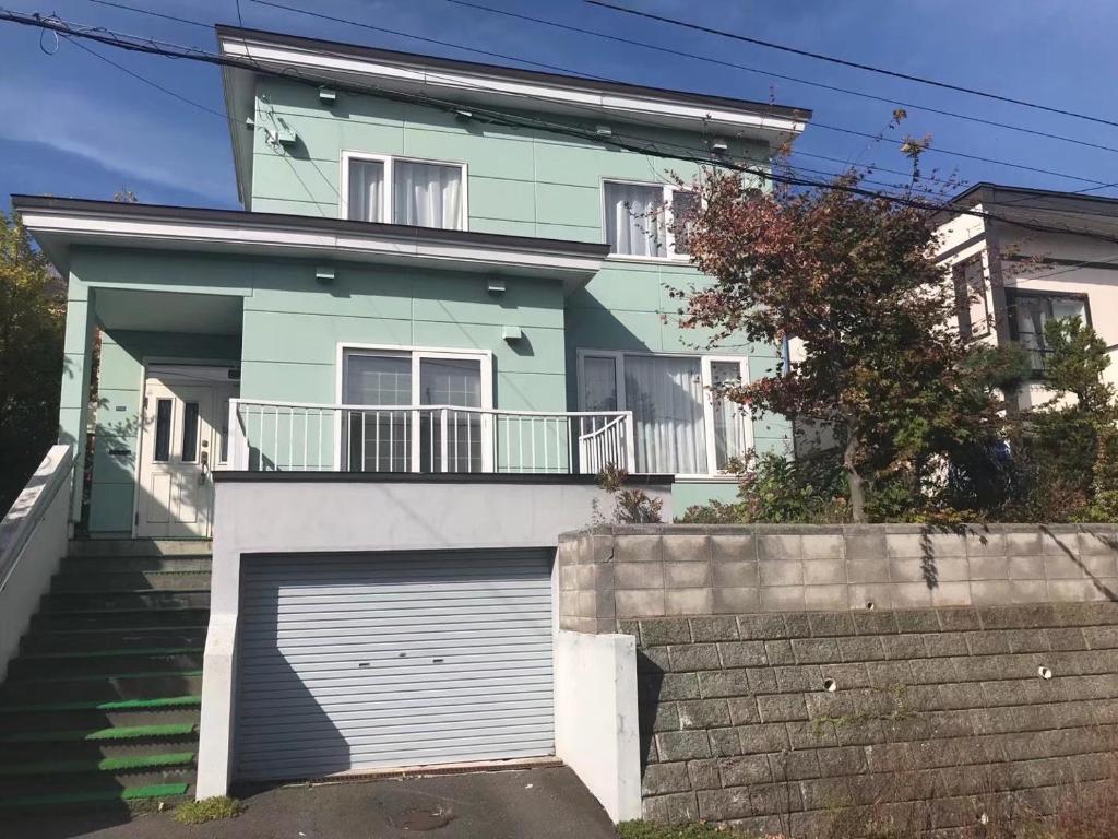 a green house with a garage in front of it at 京樽3号 1棟貸切 一軒家 3-Bedrooms Duplex Private Villa KYOTARU3 in Otaru