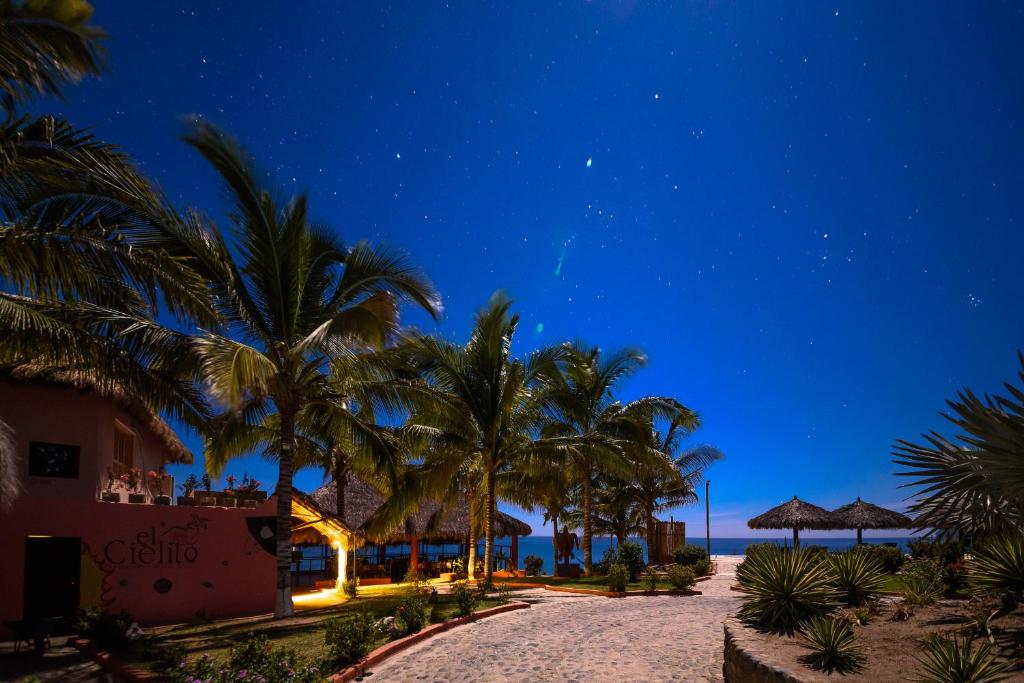 a beach at night with palm trees and a building at Cabañas El Cielito in Ipala
