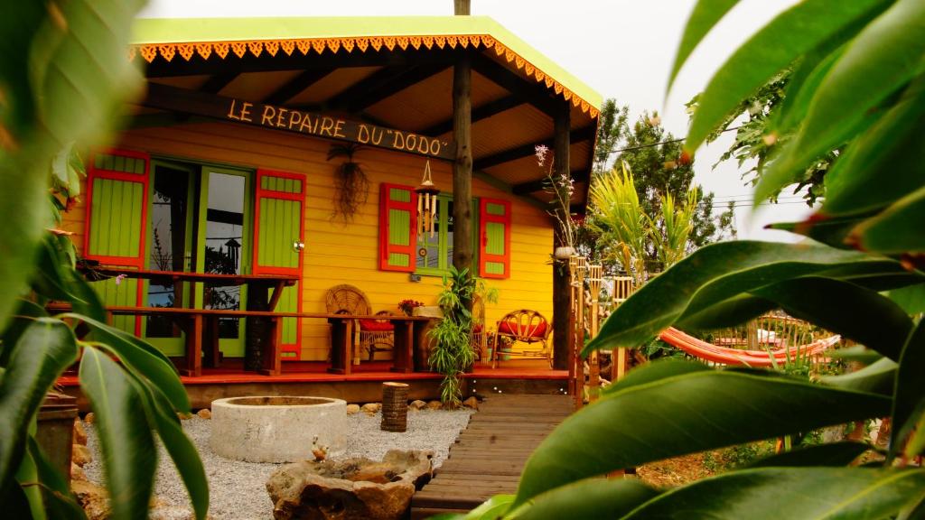 une petite maison jaune avec des portes rouges et vertes dans l'établissement Le Repaire du Dodo, à La Saline Les hauts 