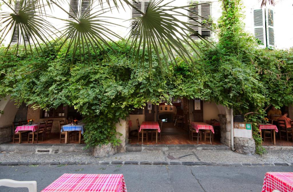 a restaurant with tables and chairs and plants at Hôtel Les Arcades in Biot