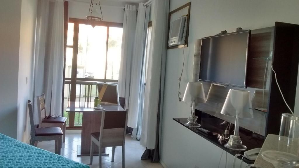 Zimmer mit TV, Tisch und Zimmer in der Unterkunft Condado Aldeia dos Reis SAHY in Mangaratiba
