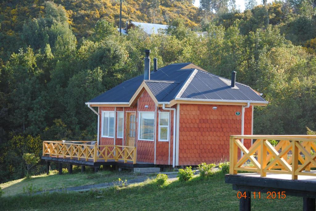 una cabaña roja con techo negro en una colina en Cabañas Trayen en Castro