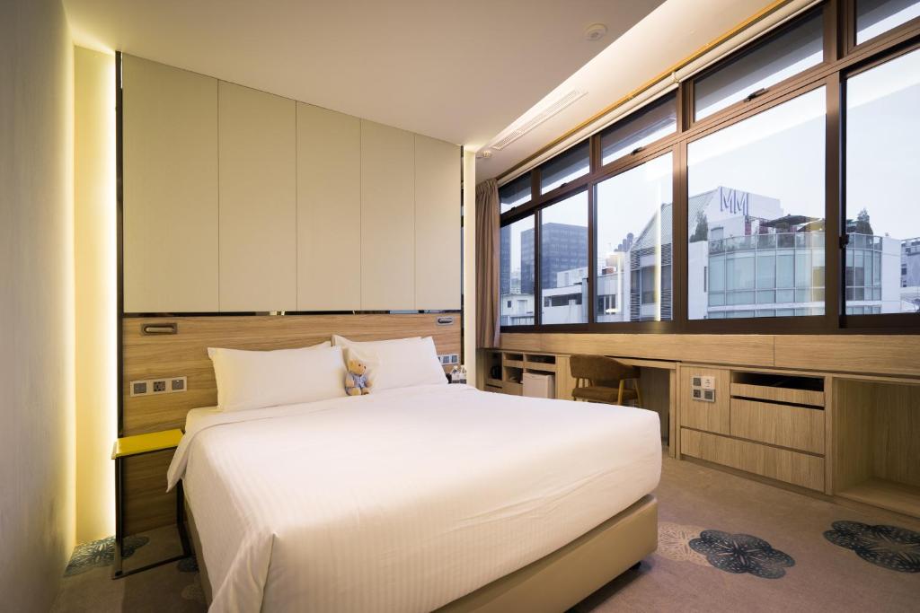 Schlafzimmer mit einem großen weißen Bett und großen Fenstern in der Unterkunft The Quay Hotel in Singapur