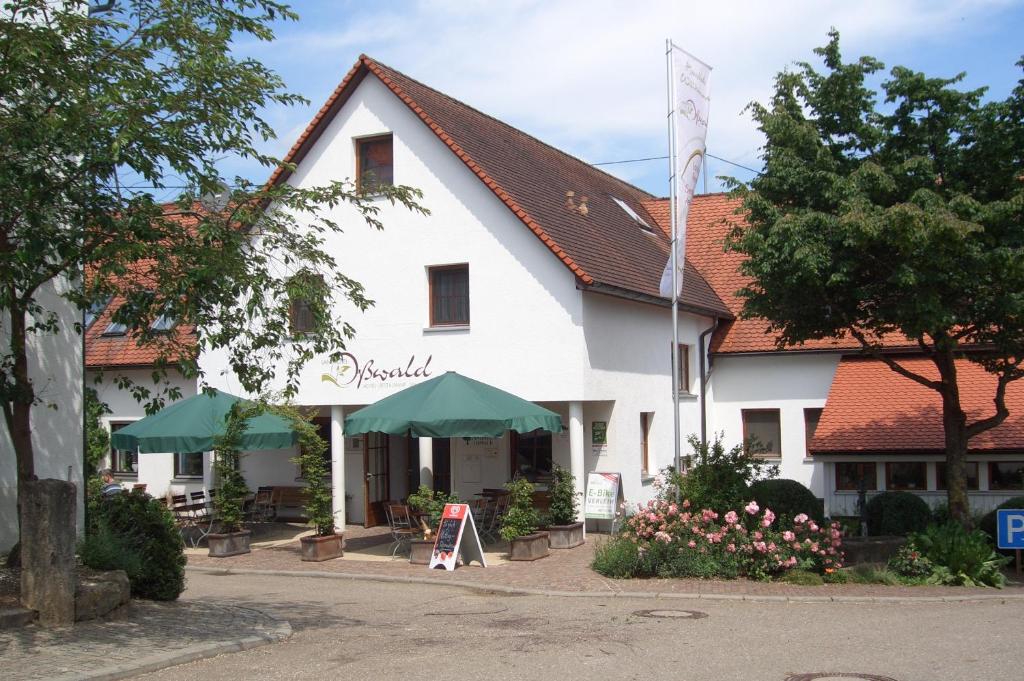 a white building with green umbrellas in front of it at Landhotel Oßwald in Kirchheim am Ries
