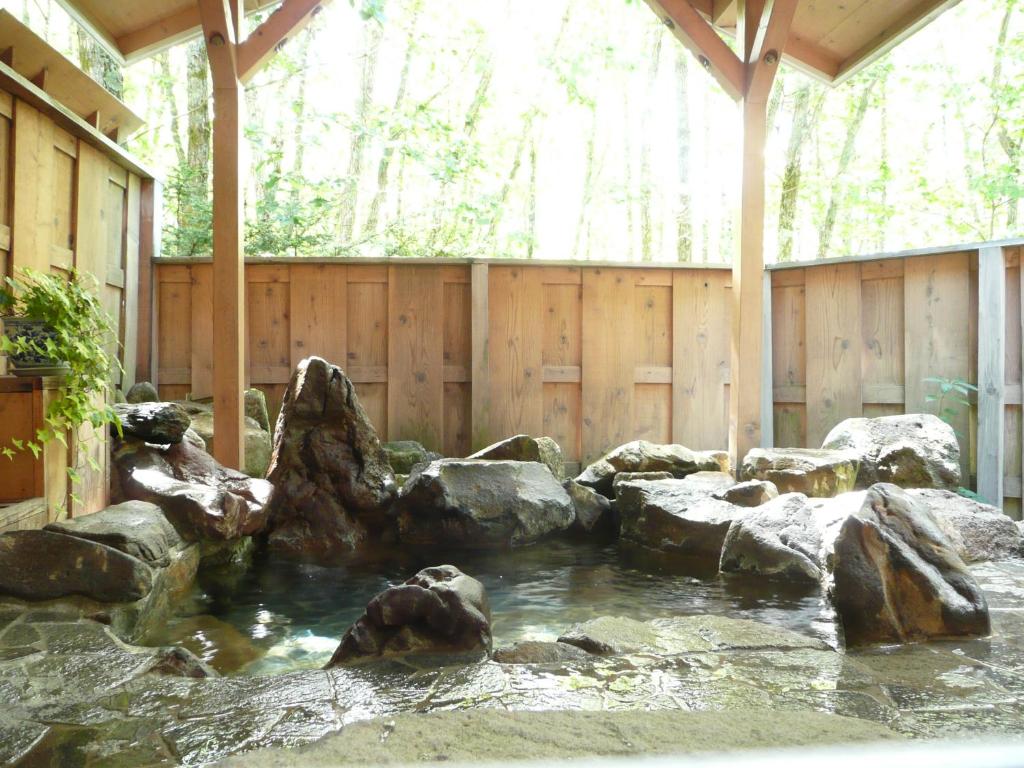 a pond with rocks in front of a wooden fence at Shikino Yado Subaru in Chino