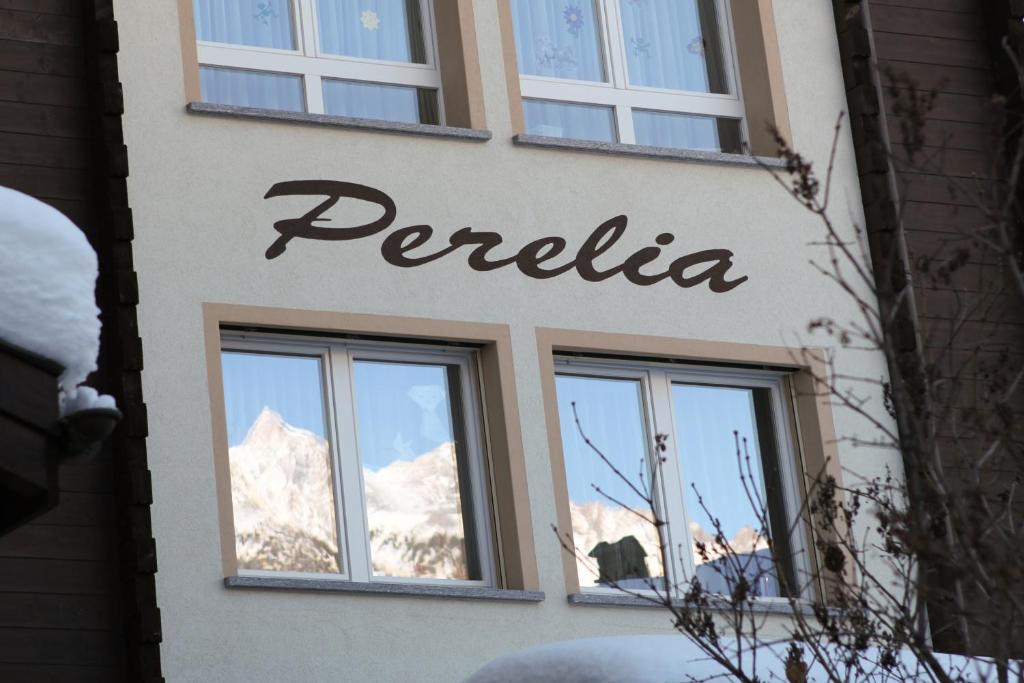 a sign on the side of a building with snow covered mountains at Haus Perelia C in Zermatt