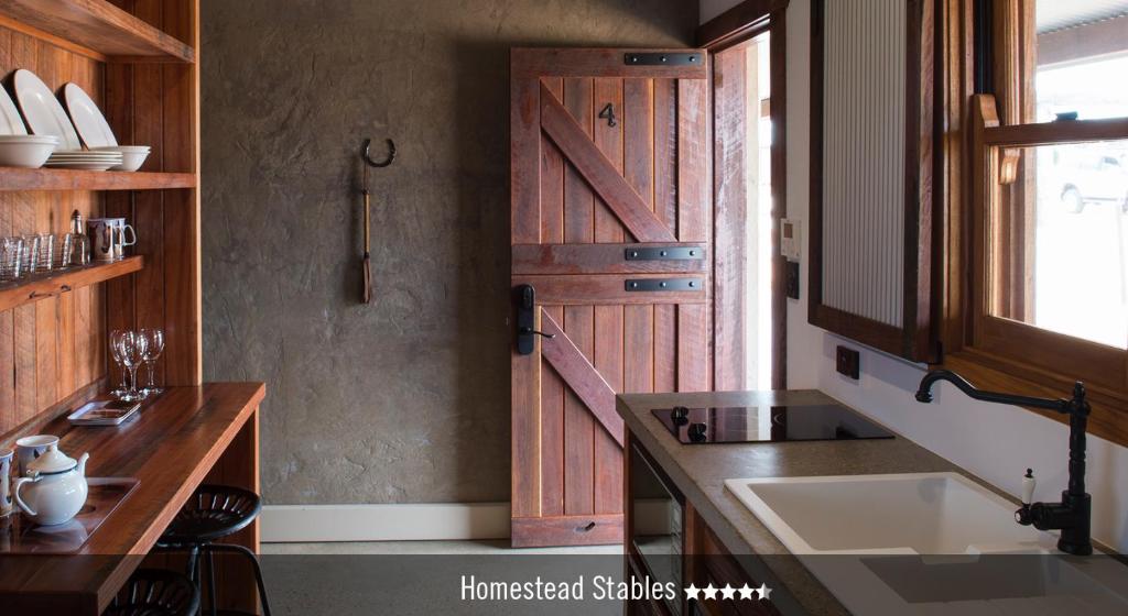 a kitchen with a wooden door and a sink at Saltbush Retreat in Longreach