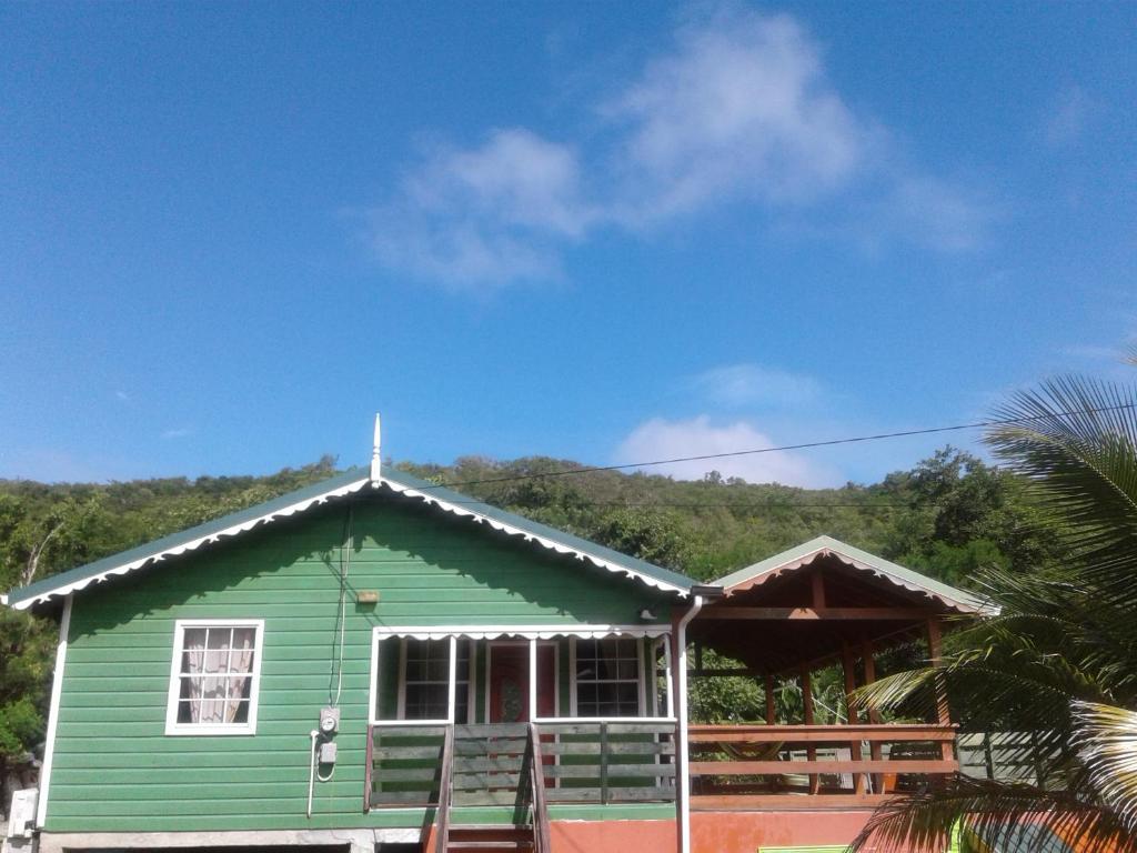 ein grünes Haus mit einem Kreuz darüber in der Unterkunft Seawind Cottage- Traditional St.Lucian Style in Gros Islet