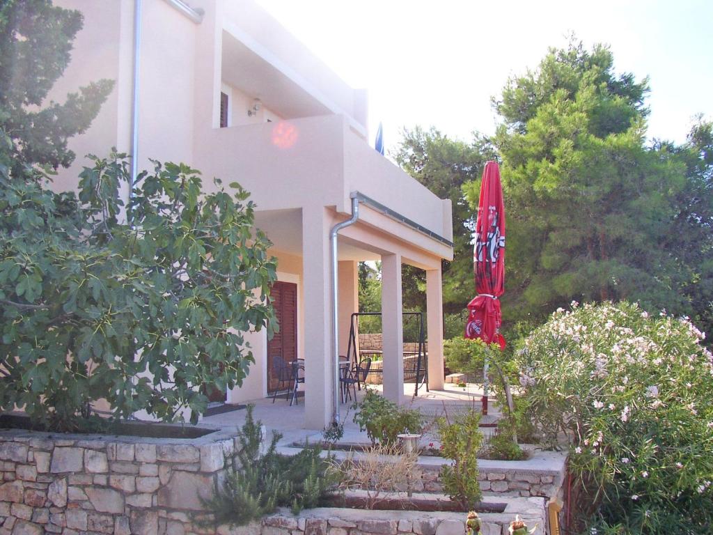 een huis met een patio en een rode parasol bij Apartments Rina in Primošten