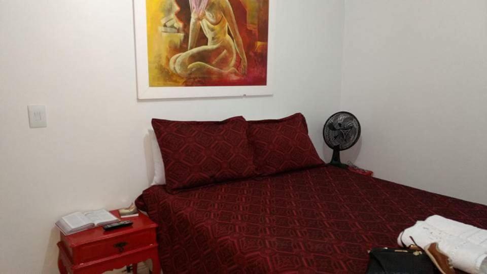 a bedroom with a bed with a red comforter at Apartamento no Guará por temporada in Brasilia