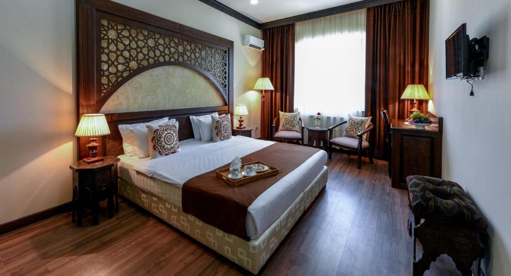 una habitación de hotel con una cama grande y una mesa en Orient Star Hotel, en Samarkand