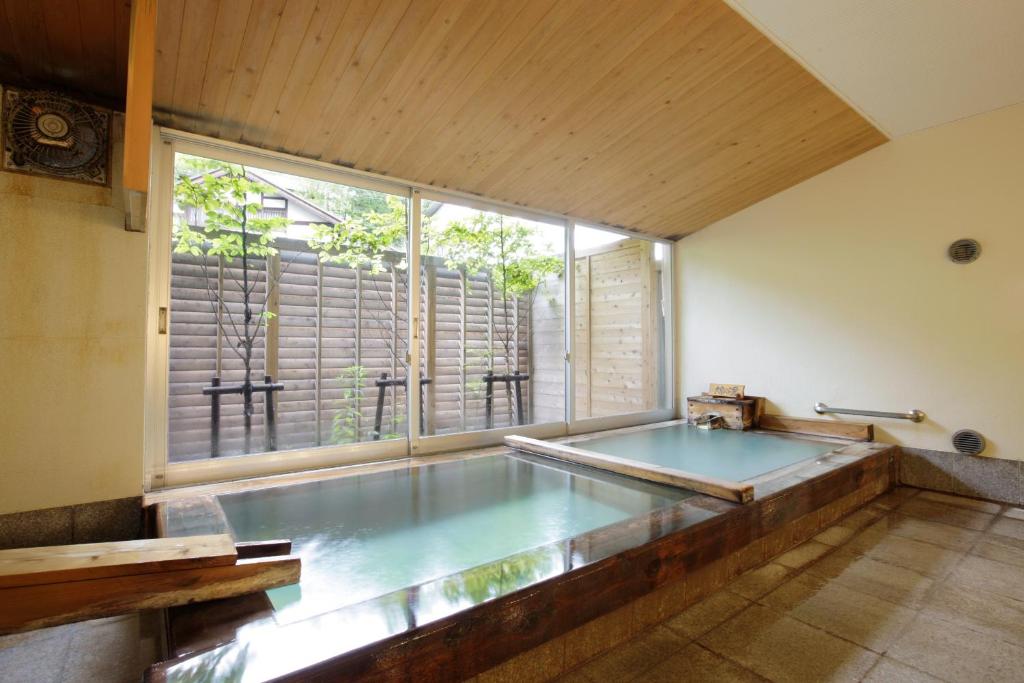 uma grande piscina num quarto com uma grande janela em Kusatsu Hotel Bekkan Wata no Yu (Adult Only) em Kusatsu